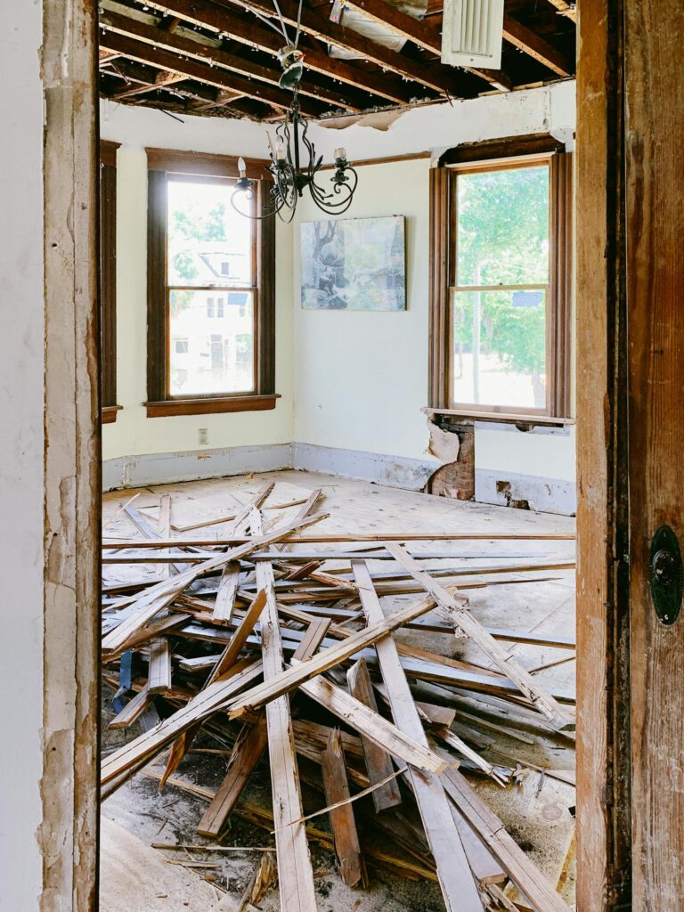 Interior room under renovation with exposed beams and planks piled on the floor.